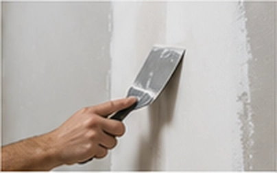 Applying compound with a drywall knife to repair a wall